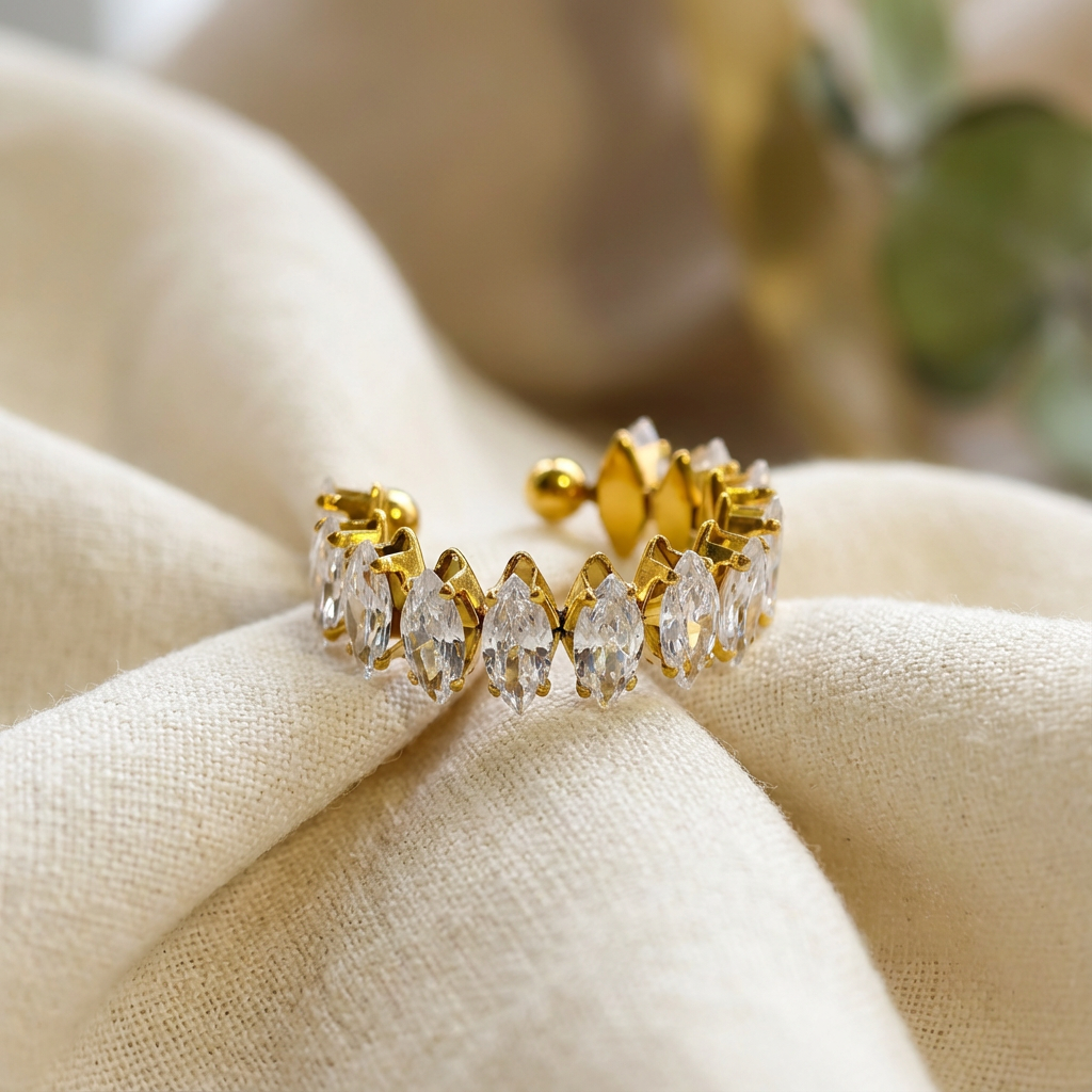 Gold-tone bangle bracelet with white enamel and rhinestone accents on a textured white stone surface