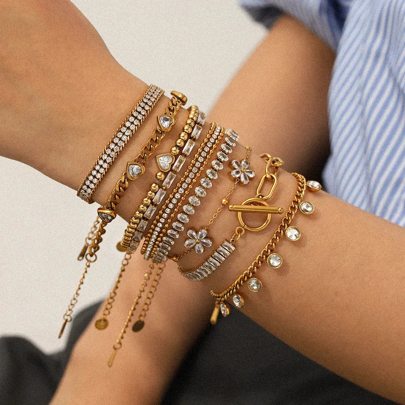 Delicate gold chain bracelet with heart charm and small clear gemstone accents on light surface