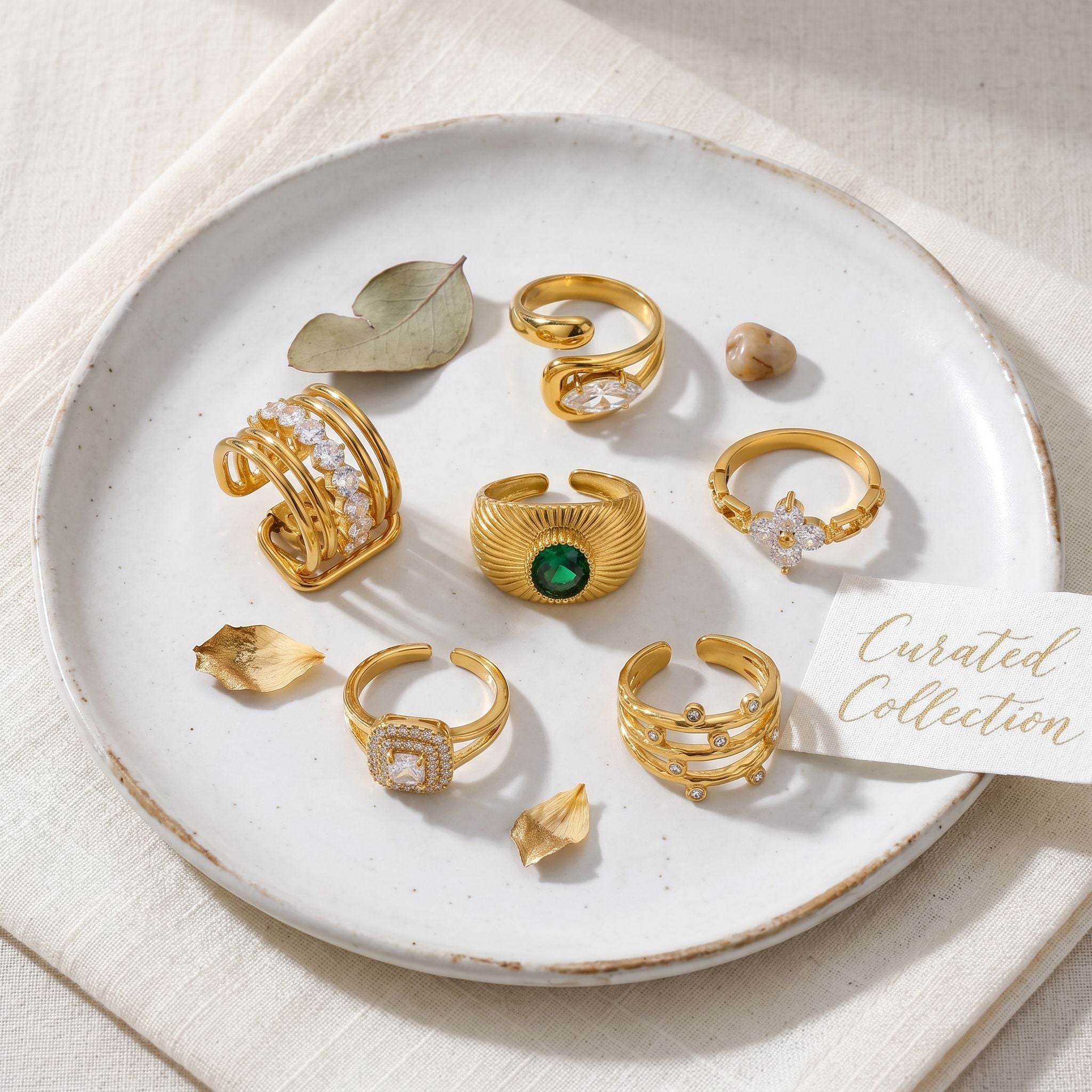 Close-up of a gold ring featuring rectangular multicolored gemstones on a neutral surface
