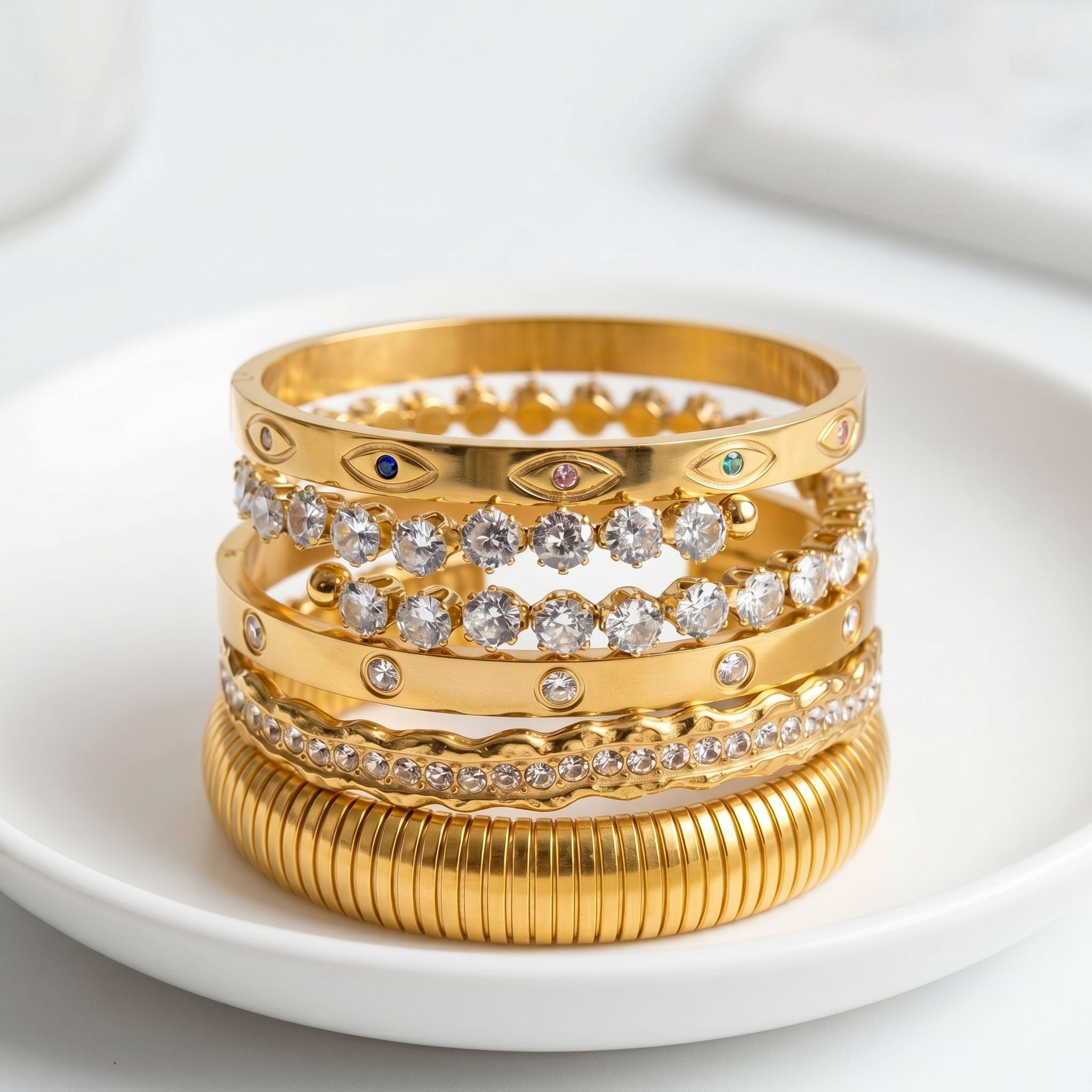 Gold bracelet with rectangular green gemstones displayed on textured white surface