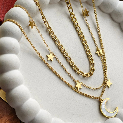 Layered gold chain necklaces with star charms and a crescent moon pendant on white beaded display
