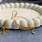 Gold feather pendant necklace with crystals on white textured display and blue surface