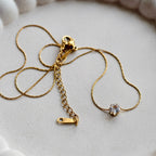 Gold necklace with a clasp on a white ceramic dish