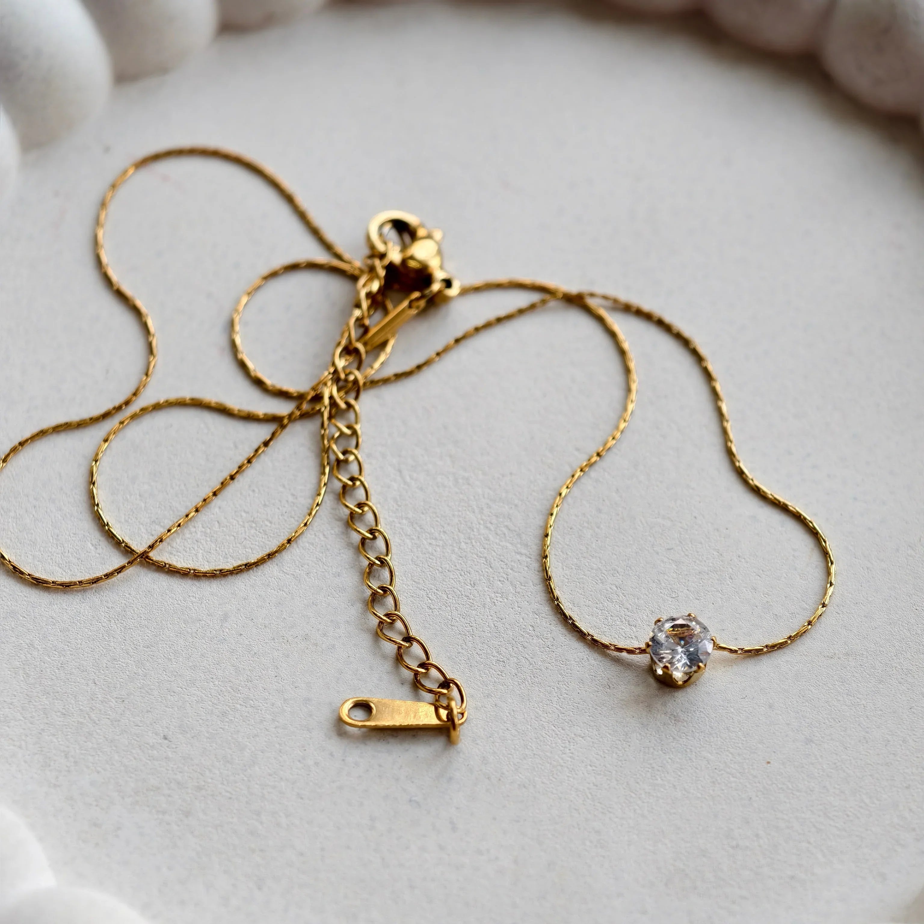 Gold necklace with a clasp on a white ceramic dish
