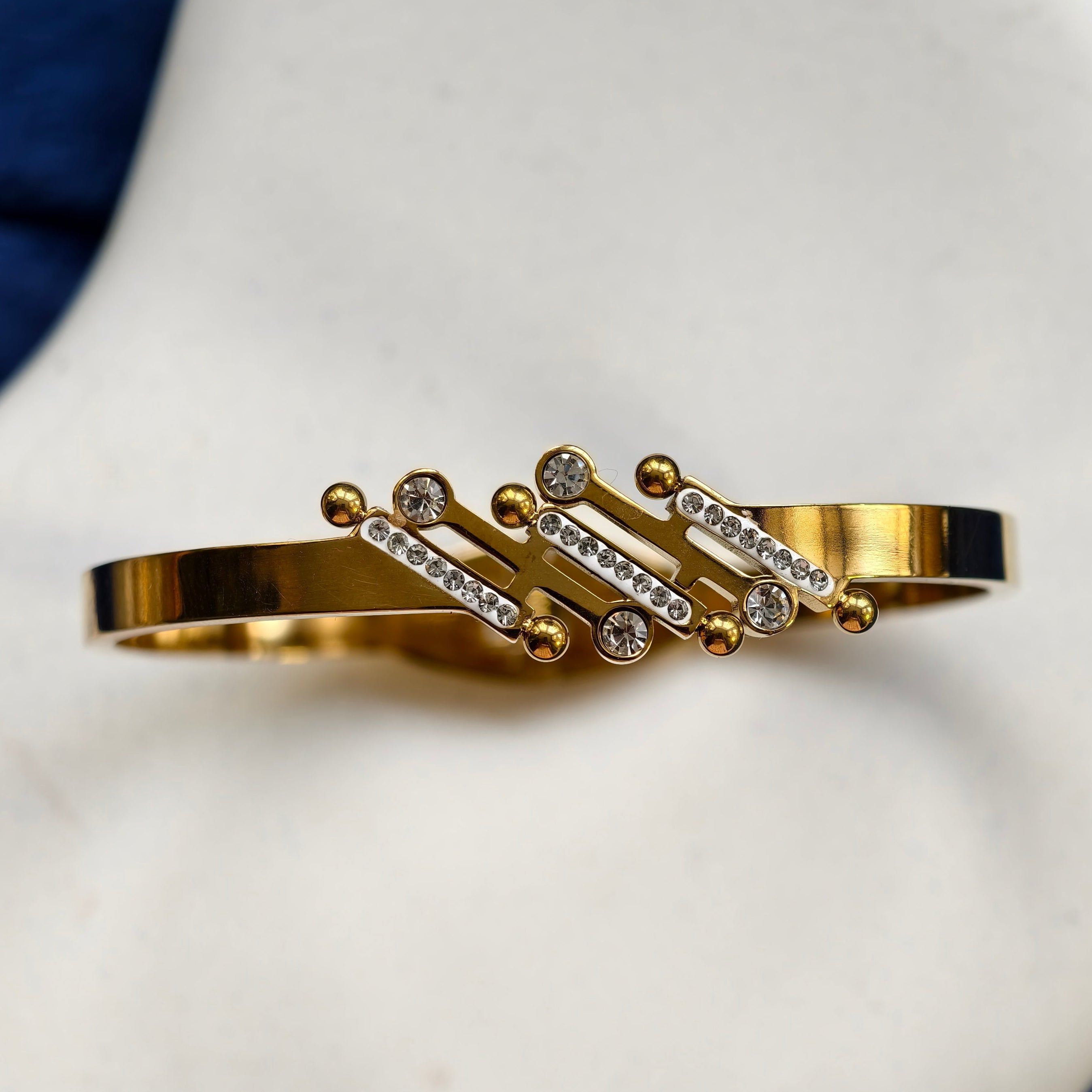 Gold bracelet with embedded stones on a white surface