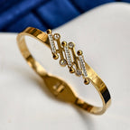 Gold bracelet with diamond accents on a white surface with blue background