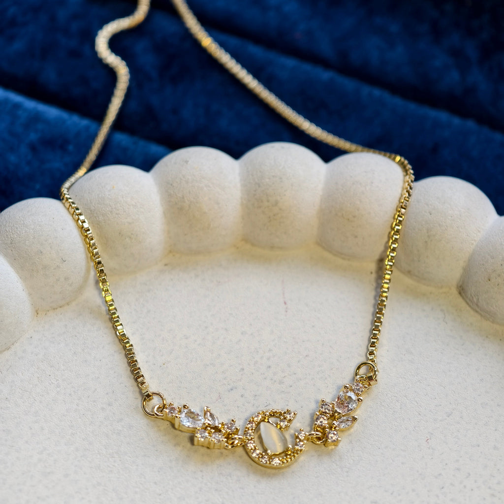 Gold necklace with a decorative clasp on a white stand against a blue fabric background