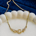 Gold necklace with a decorative clasp on a white stand against a blue fabric background