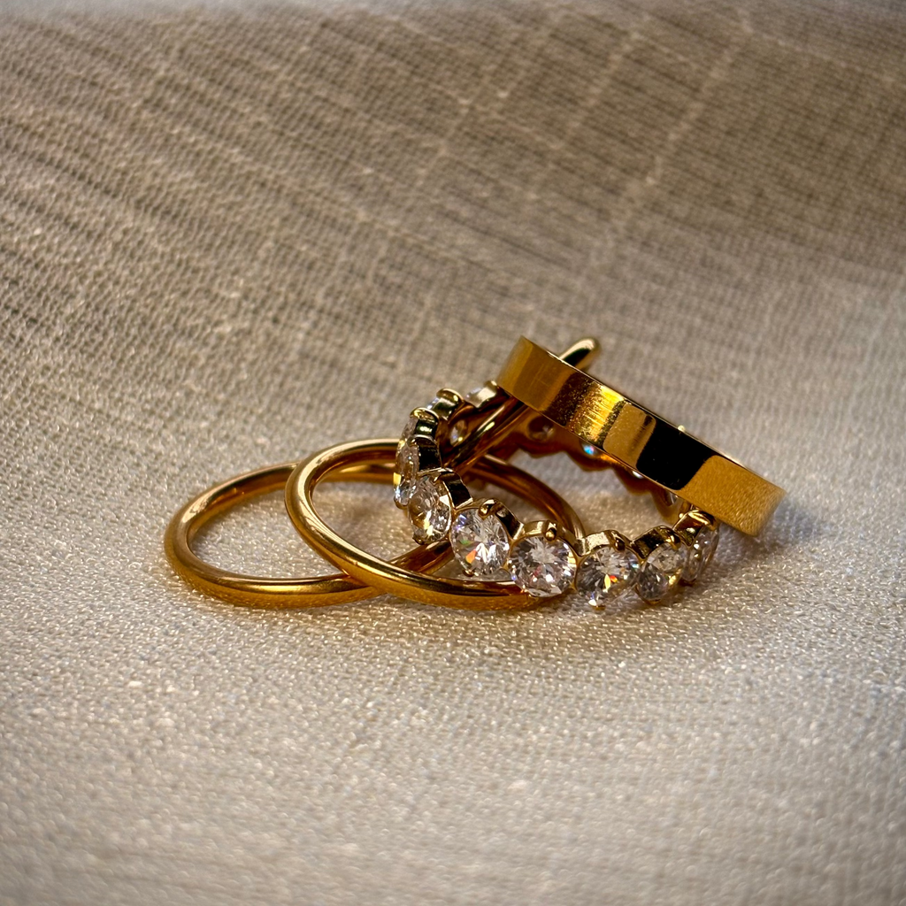Gold hoop earrings with clear gemstones on a beige fabric background