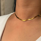 Gold necklace on a person wearing a white top