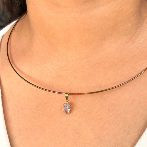 Necklace with a clear pendant on a person wearing a white top.