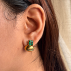 Gold earring with green gemstone worn by a person
