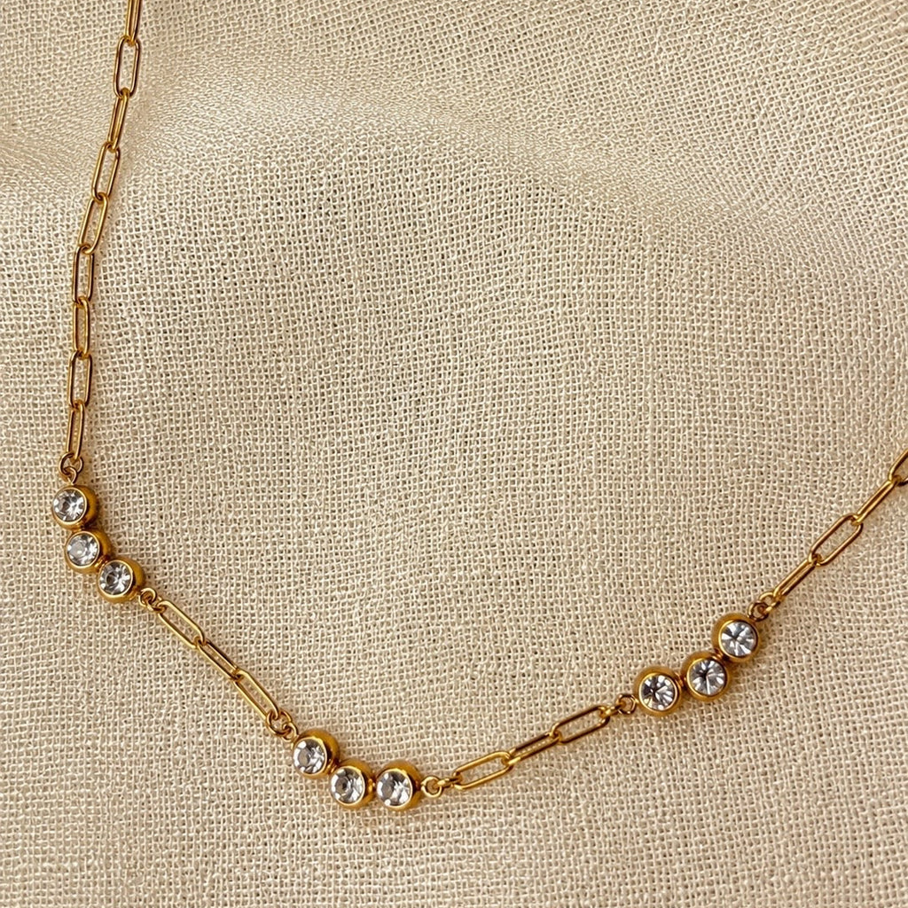 Gold necklace with small diamonds on a beige fabric background