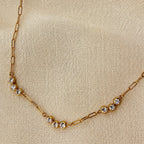 Gold necklace with small diamonds on a beige fabric background