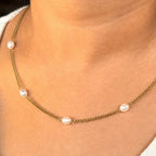 Necklace with pearls worn by a person, close-up on skin