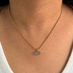 Gold necklace with a pendant on a person wearing a white top