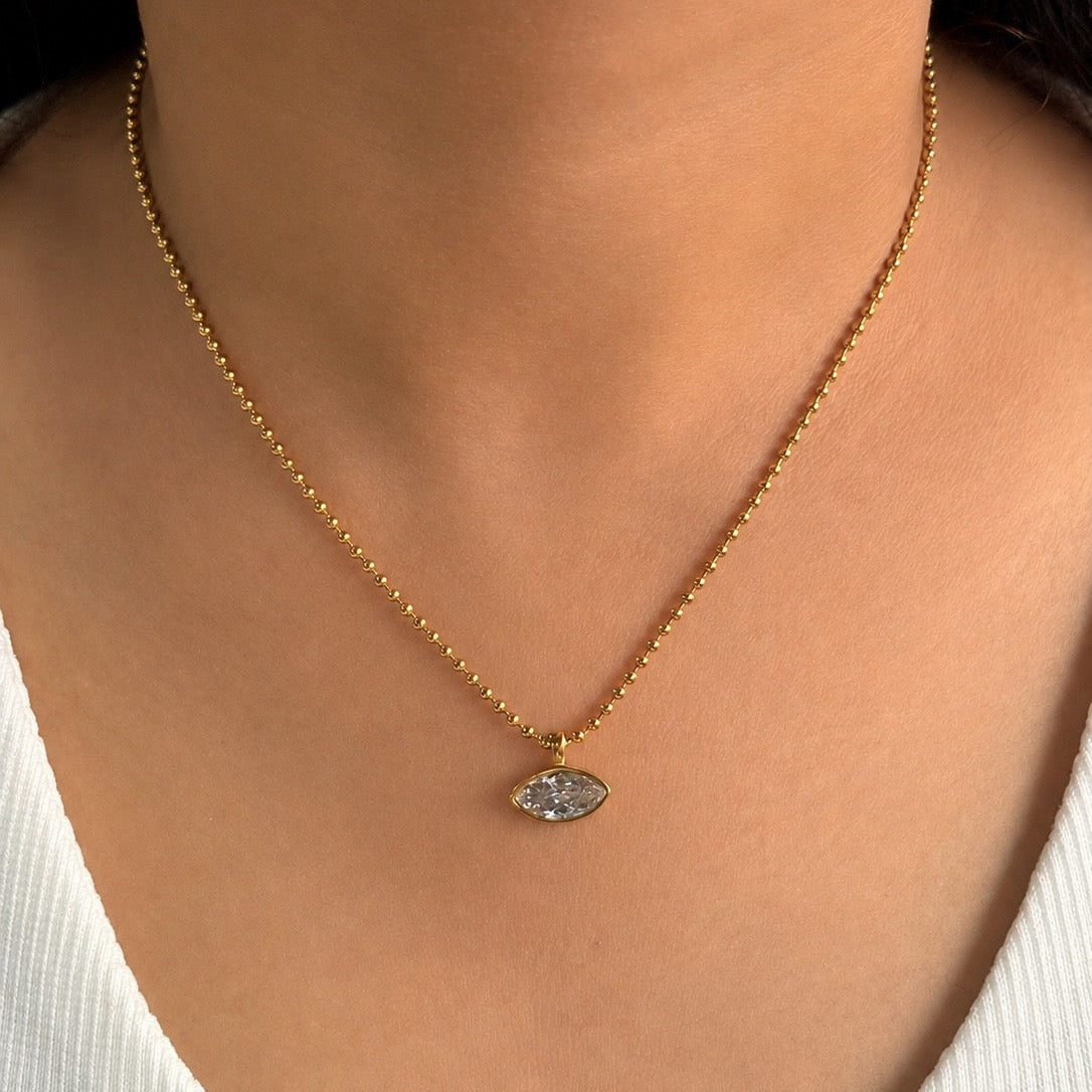 Gold necklace with a pendant on a person wearing a white top