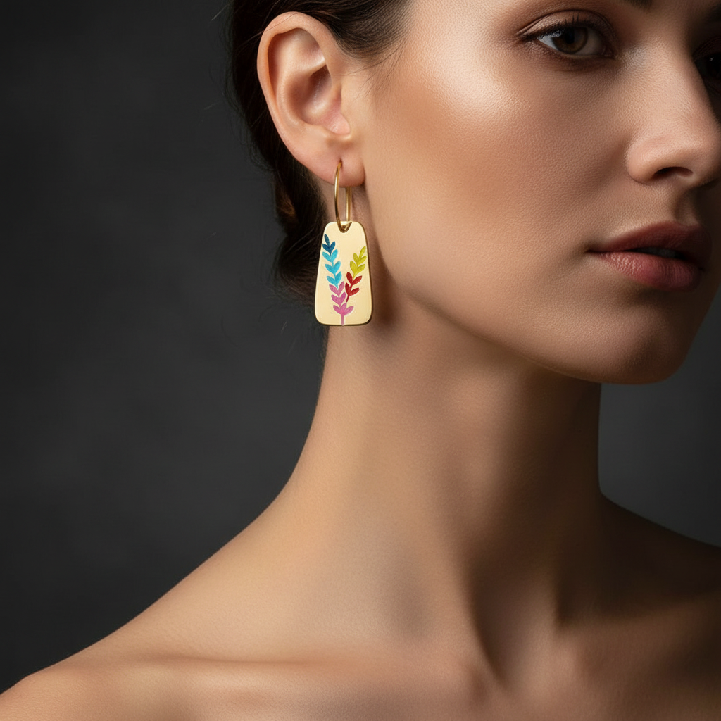 Pretty Shimmering Things Global Aurora gold-tone drop earrings featuring a vibrant multi-colored leaf motif on a model