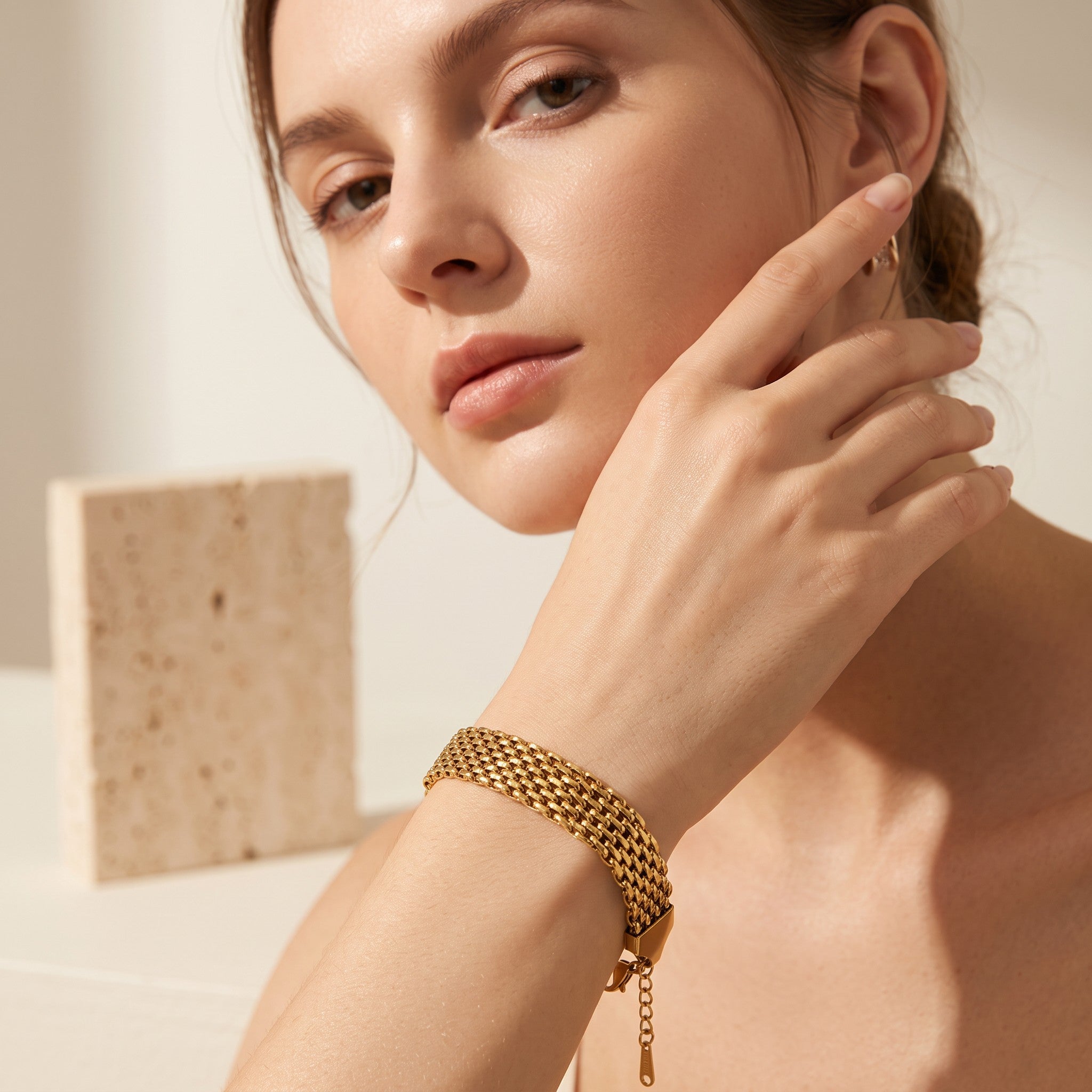 Pretty Shimmering Things gold-tone multi-strand woven stainless steel bracelet worn by a woman
