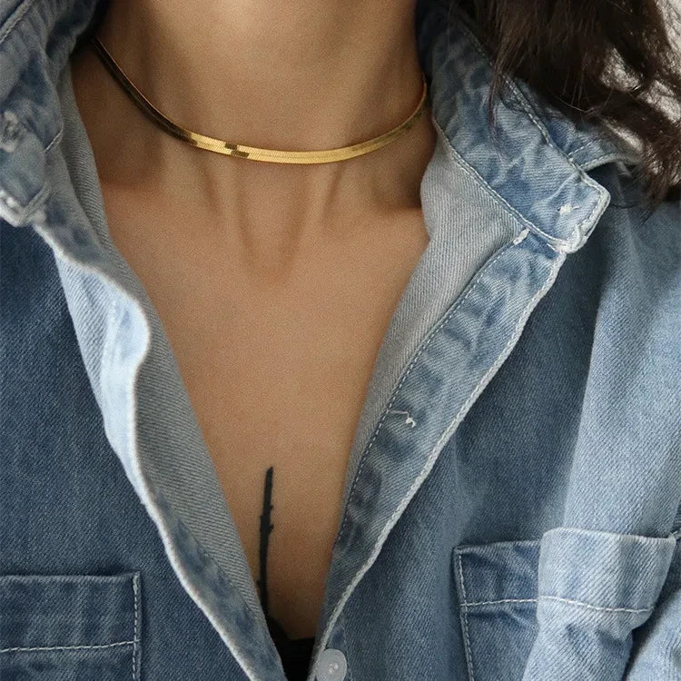 Pretty Shimmering Things gold-tone herringbone chain necklace worn by a model in a denim shirt.