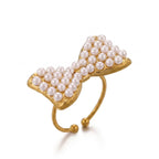 Pretty Shimmering Things gold-tone bow statement ring featuring delicate faux pearls on an adjustable open band.