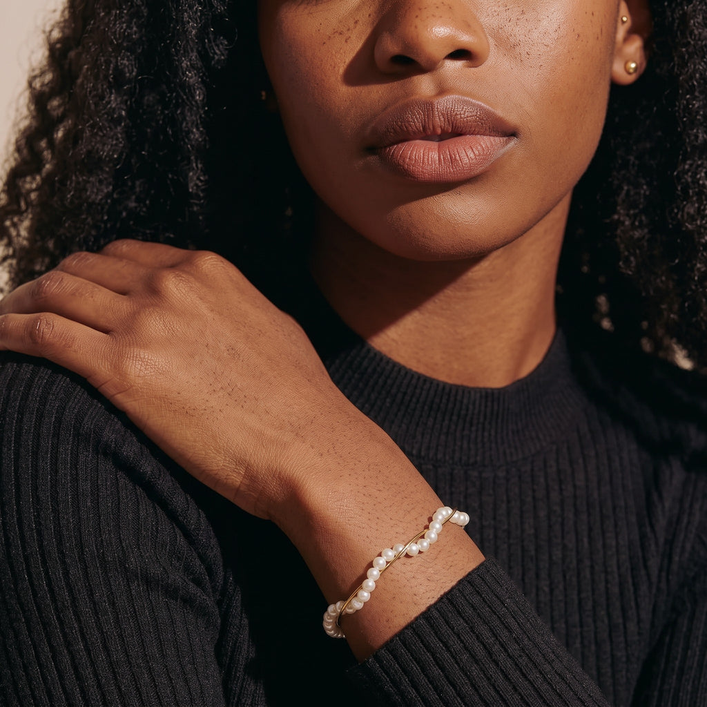 Pretty Shimmering Things Madison pearl twist bracelet in gold-tone brass worn on a model in a black ribbed top.